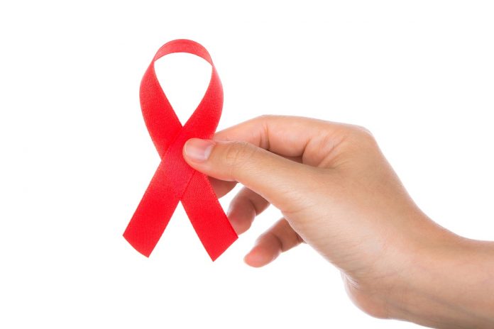 AIDS ribbon in hand isolated on white background